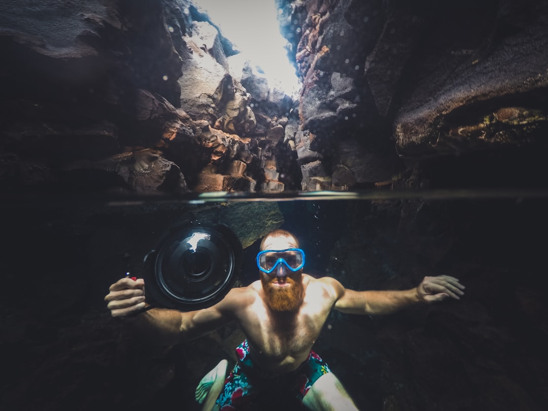 man in body of water between cliffs during daytime