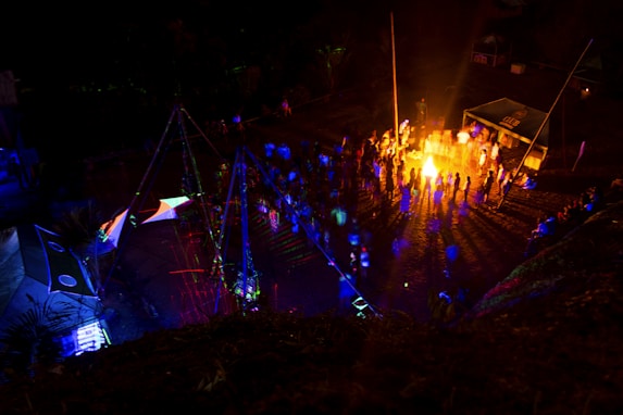 A vibrant outdoor gathering with people enjoying food and music around a bonfire.