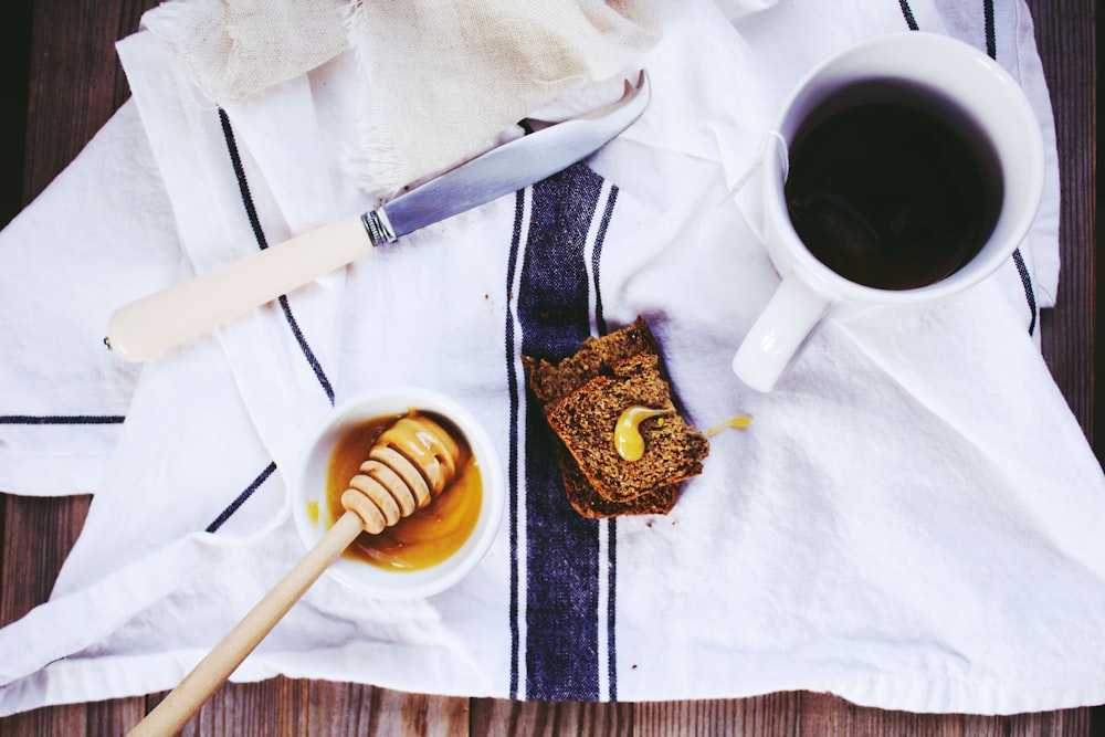 flat lay photography of white knife, honey dipper on bowl, and coffee mug