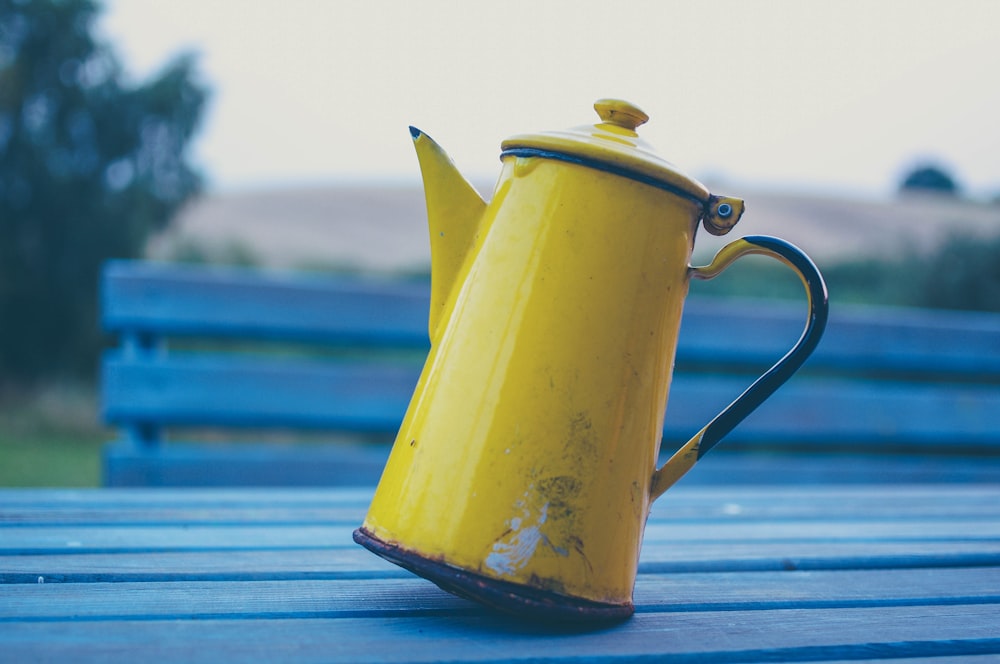 yellow kettle on gray wooden table