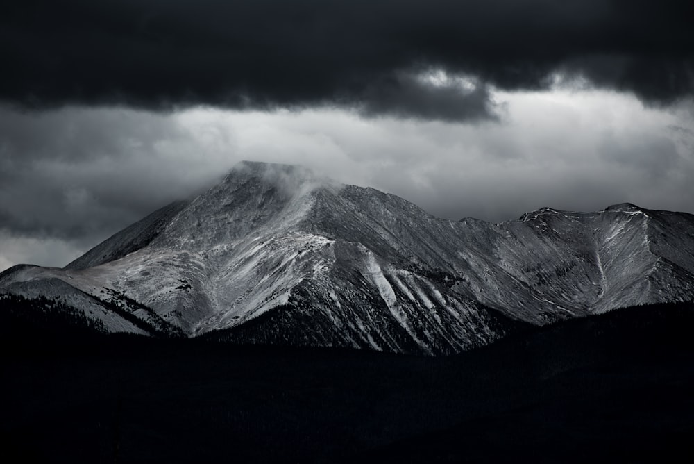 foto em tons de cinza das montanhas sob o céu nublado