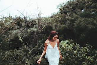 A serene woman in her 40s walking through a sunlit forest path, embodying calm and vitality.