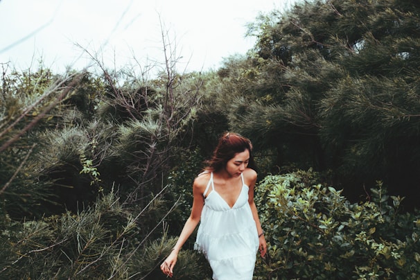 A serene woman in her 40s walking through a sunlit forest path, embodying calm and vitality.