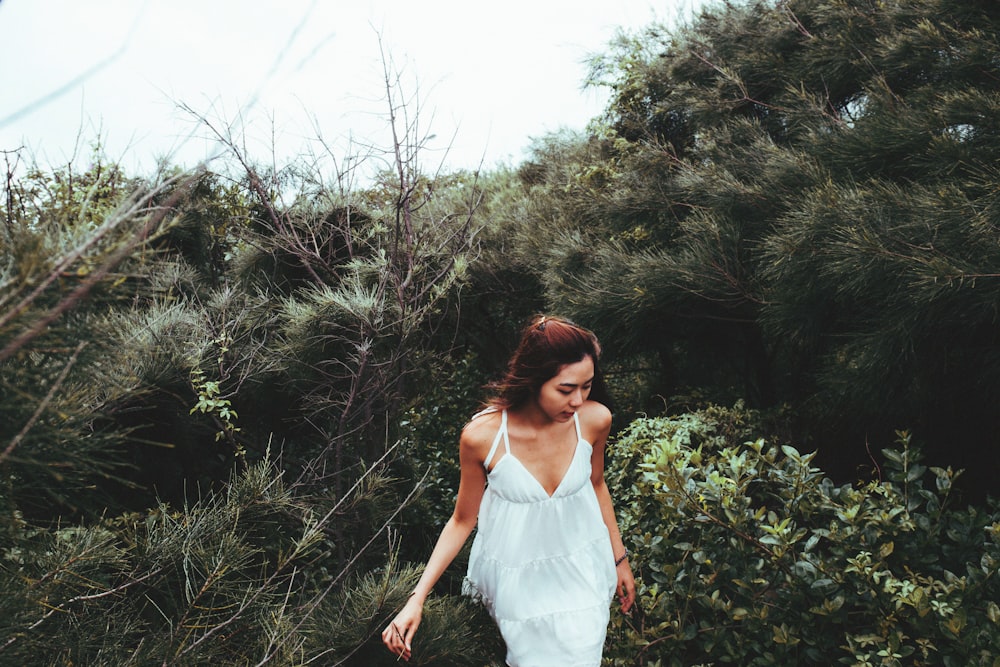 landscape photography of woman behind green leafed trees during daytime