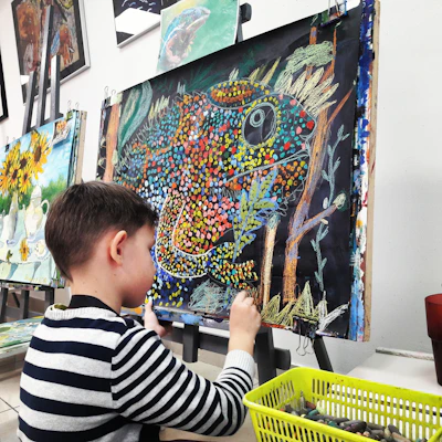 A child quietly engaged in expressive arts painting with soft watercolors in a warm, sunlit room.