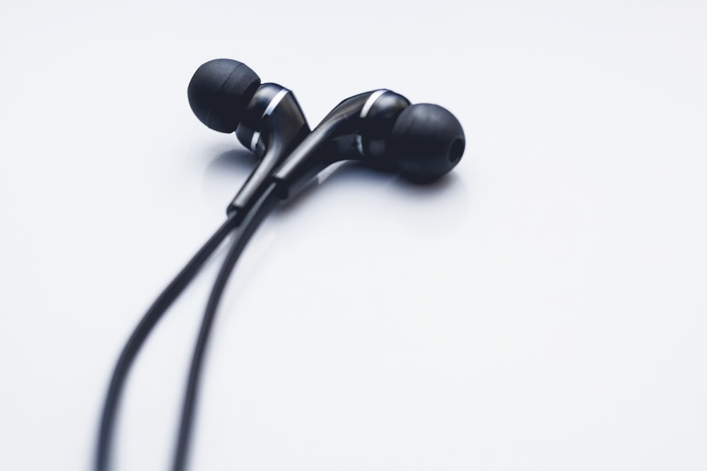 a pair of black ear buds on a white surface