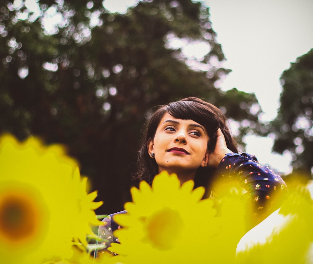 woman holding hair near trees at daytime