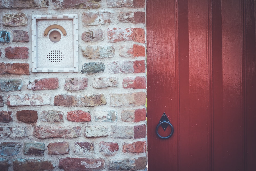 un mur de briques avec une porte rouge et une poignée de porte rouge