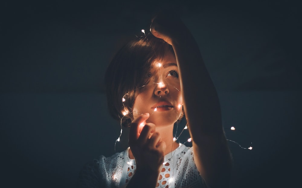 mujer sosteniendo una cuerda de luz en una habitación oscura