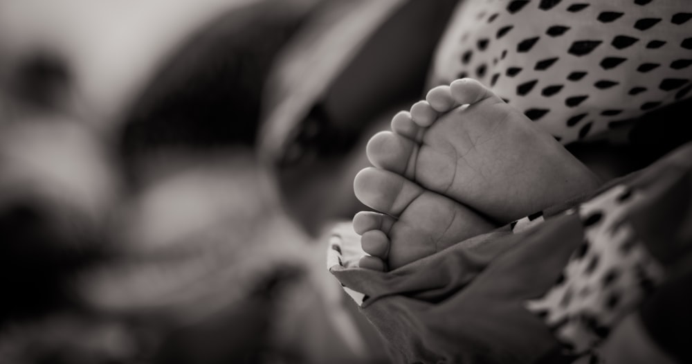 foto in scala di grigi dei piedi del bambino