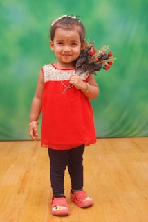 A happy child holding a small bouquet of wildflowers, dressed in a charming outfit
