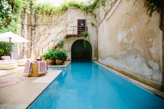 A serene heated pool framed by terracotta walls and lush greenery in Moroccan style.