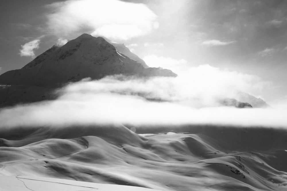 Foto en escala de grises de una montaña cubierta de niebla