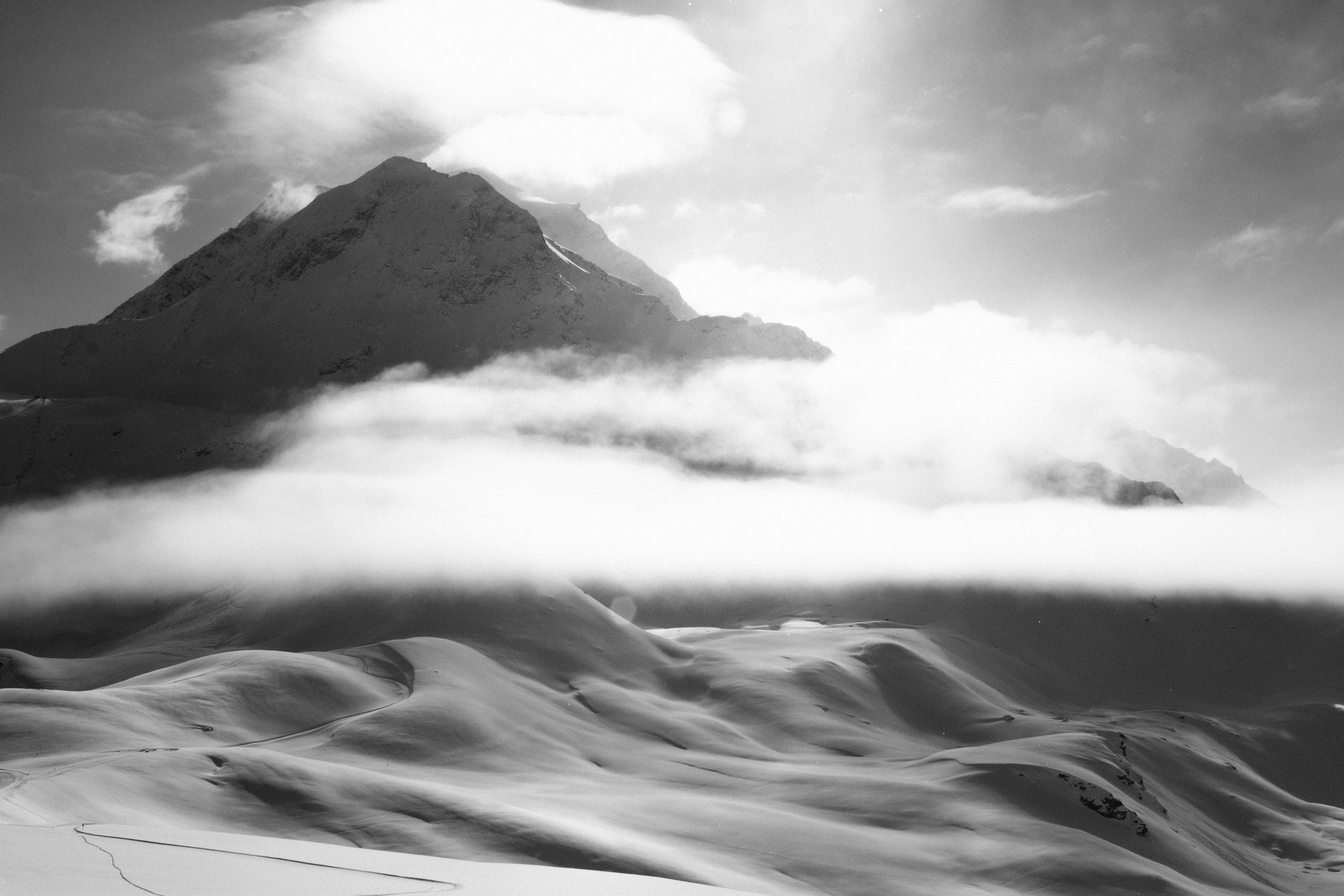 grayscale photo of mountain covered by fogs