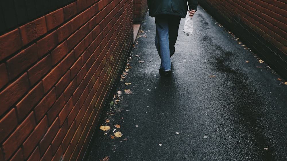 person walking on black-paved alley