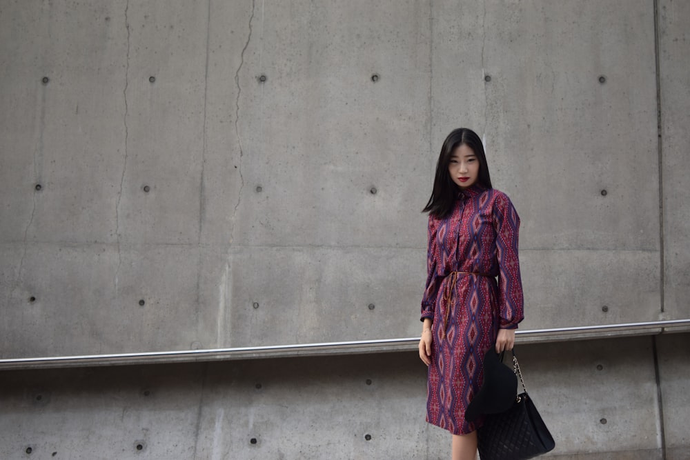 woman holding bag standing beside wall