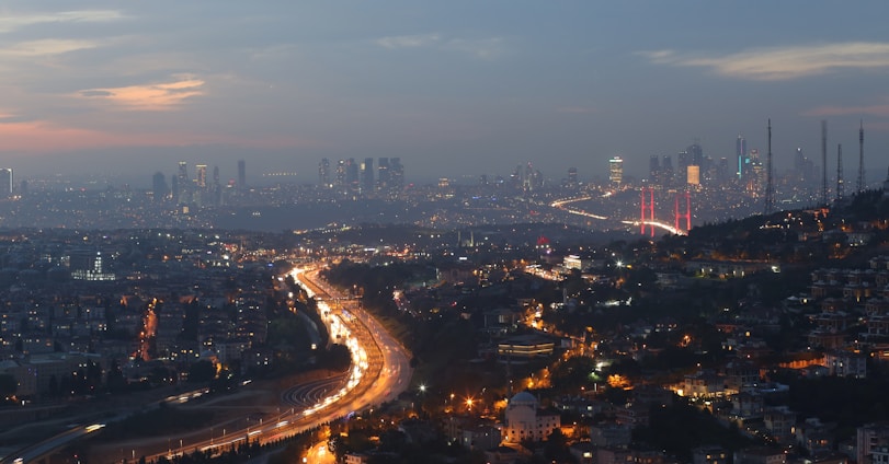 A panoramic view of a newly constructed African highway cutting through a vibrant cityscape at sunset.