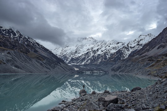 body of water overlooking mountains during daytime in Aoraki/Mount Cook National Park New Zealand