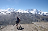 A person standing on a mountain peak, looking towards the horizon.