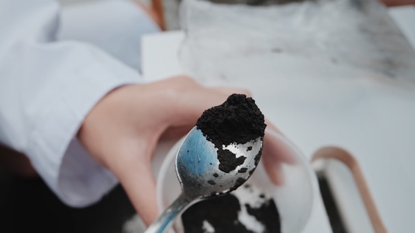Close-up of shilajit powder being scooped with a wooden spoon.