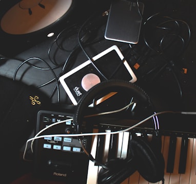 flat-lay photo of headphones, MIDI keyboard, and speaker on black surface