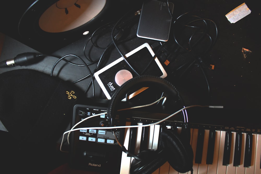 flat-lay photo of headphones, MIDI keyboard, and speaker on black surface