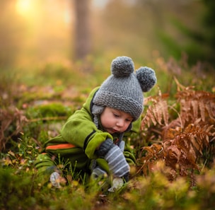 selective focus photo of baby on green grass field