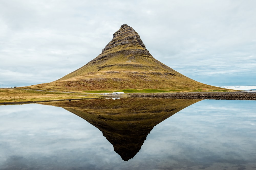 Montagne marroni circondate da uno specchio d'acqua durante la fotografia diurna