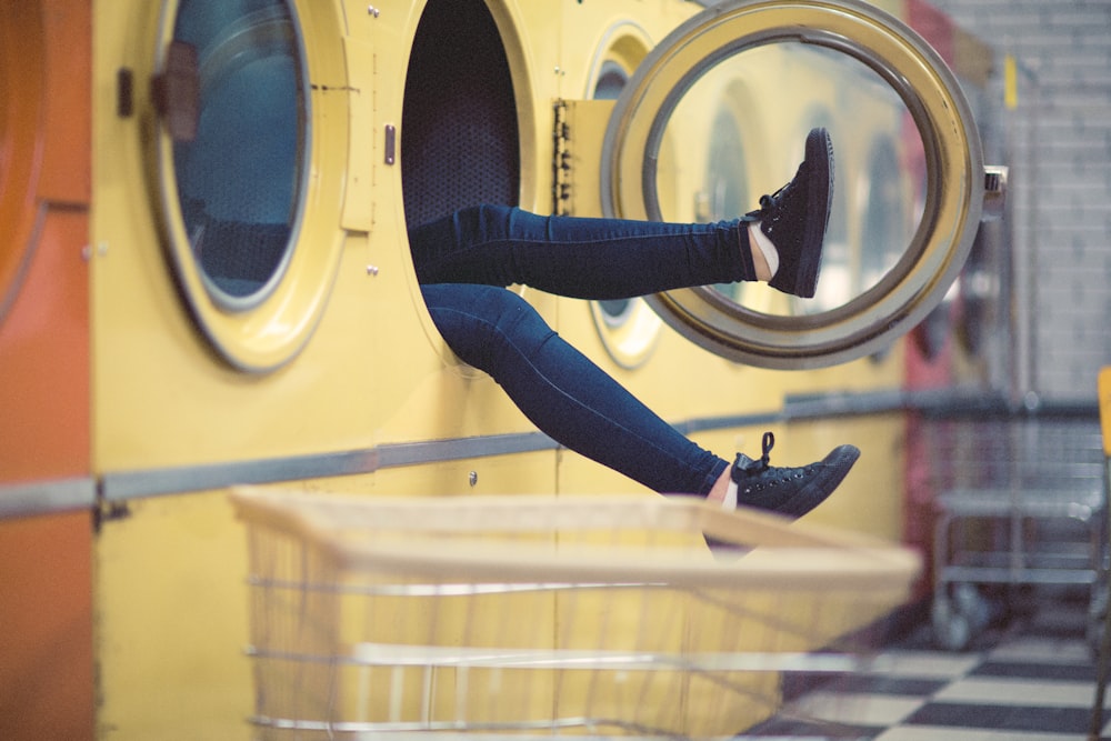 person wearing blue fitted jeans inside laundry machine during daytime