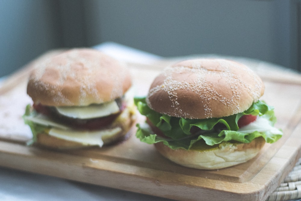 two burgers on brown wooden chopping board