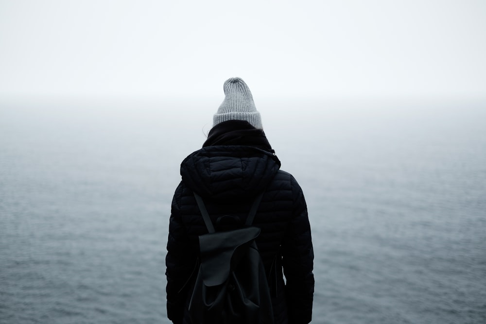 person wearing black jacket standing in front of the ocean