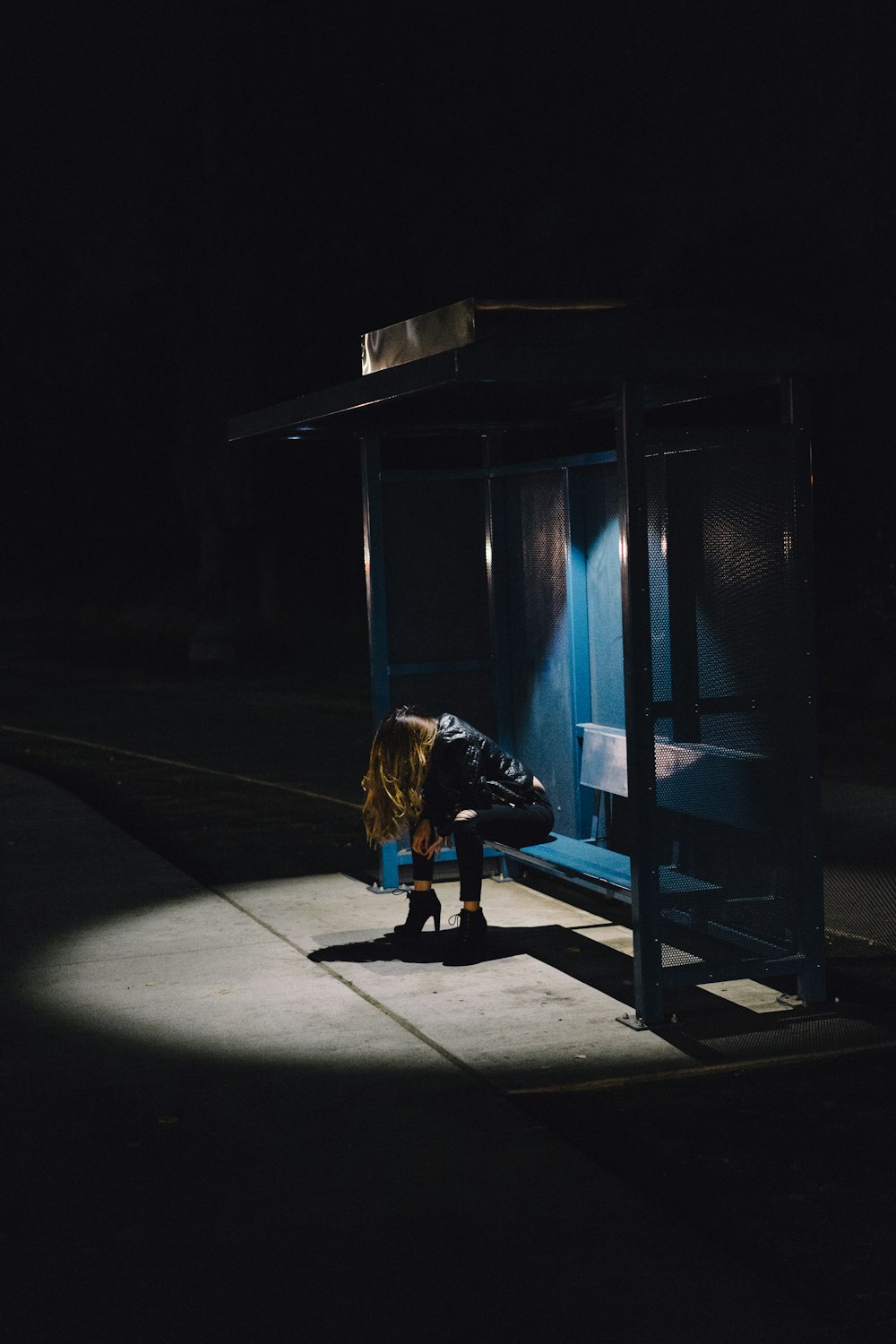 Frau sitzt nachts auf schwarzer Hantelbank