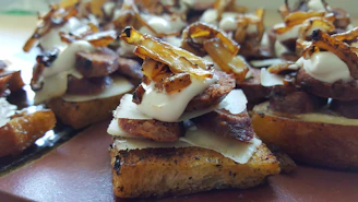 A close-up of a chef layering fresh ingredients on toasted artisan bread in a bright kitchen.