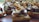 A close-up view of a gourmet appetizer featuring toasted bread topped with slices of roasted meat, caramelized onions, thin cheese slices, and a dollop of creamy sauce. The dish is artistically arranged and appears savory and delicious.