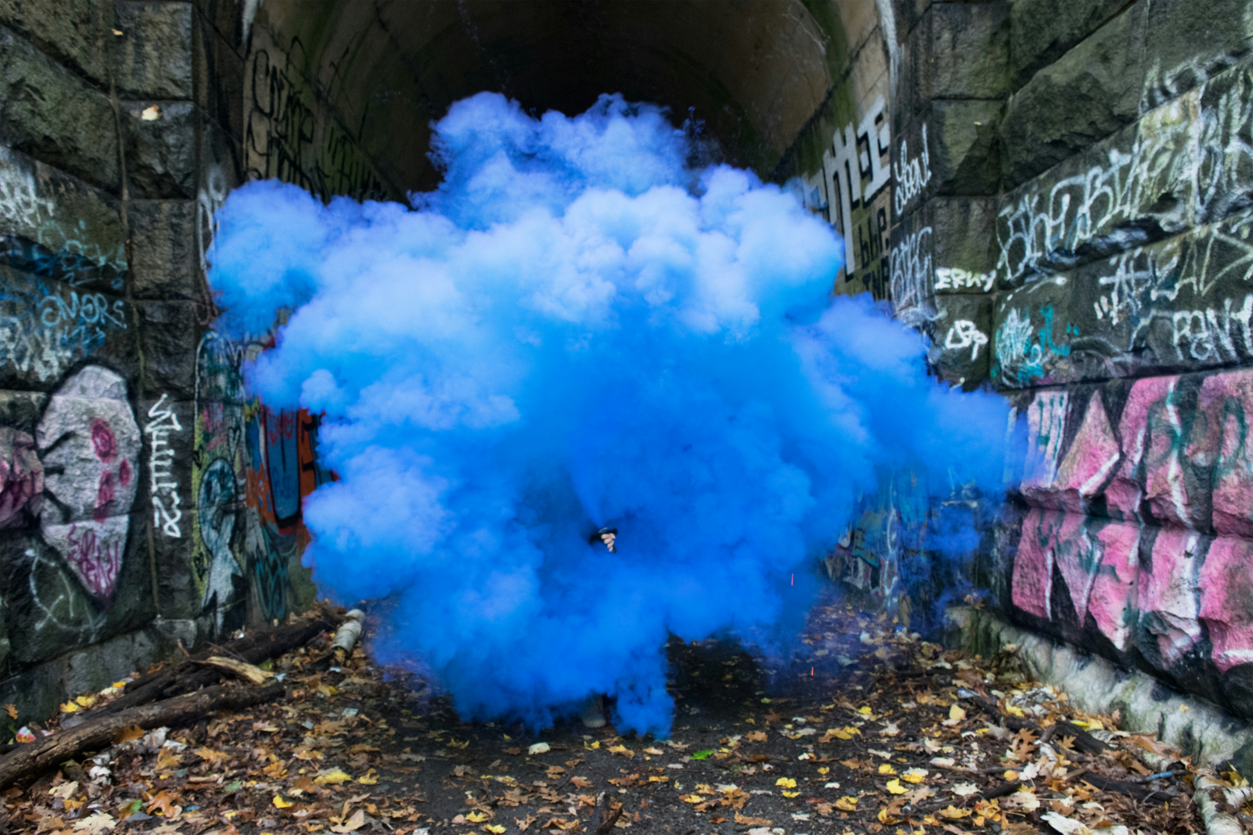 photo of blue smoke beside walls with graffiti