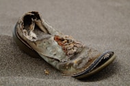 unpaired brown and black shoe on sand