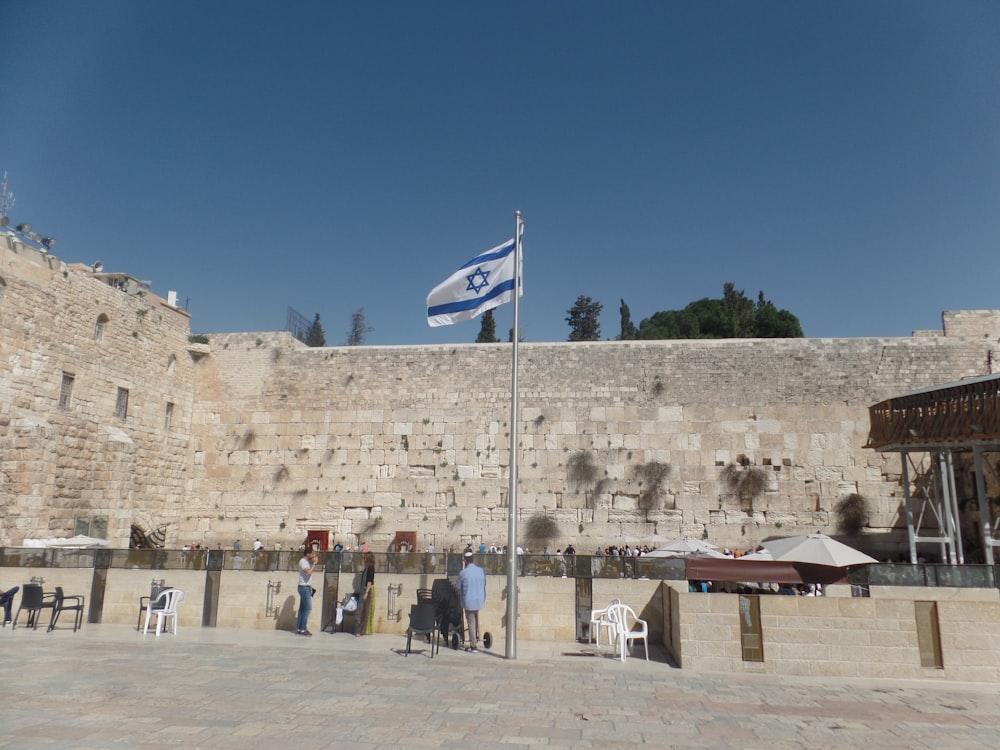 People talking to each other in a gathering spot in Israel, with the nation's flag raised high.