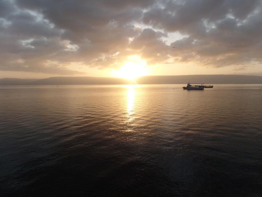 Um pôr do sol no horizonte de um oceano coberto de nuvens.