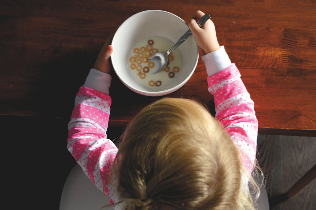 Young child eating a bowl of cereal at a kitchen table, illustrating everyday nutrition and children's gut health in the UK