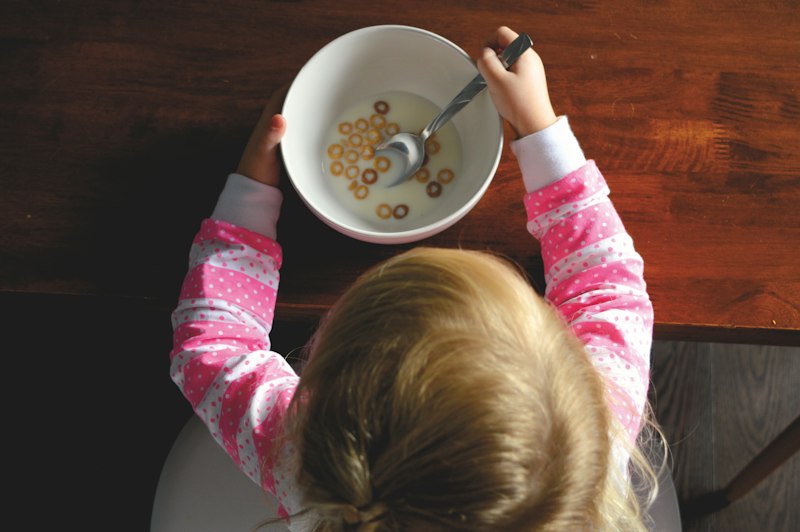 Niña desayunando cereal en la mesa