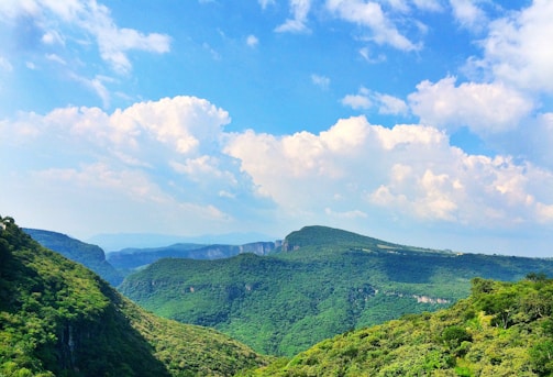 A sweeping landscape of lush green hills under a bright blue sky.