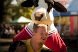 smiling man wearing yellow polo shirt standing near cattle cosplay