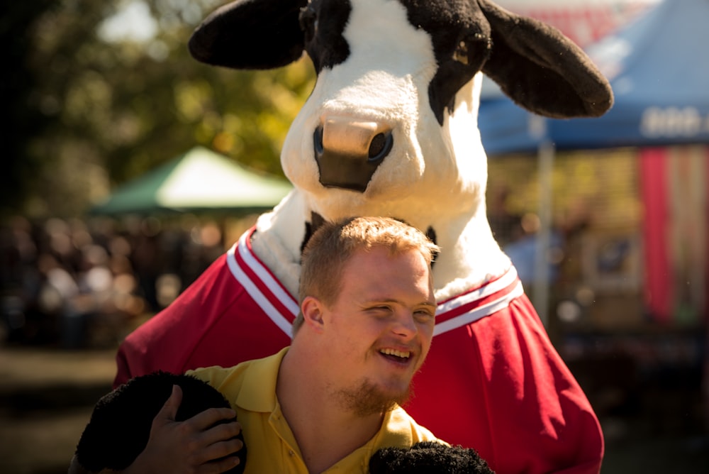 homem sorridente vestindo camisa polo amarela em pé perto do cosplay do gado