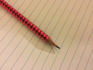 A close-up of a sharpened pencil resting on a clean, white notebook page.