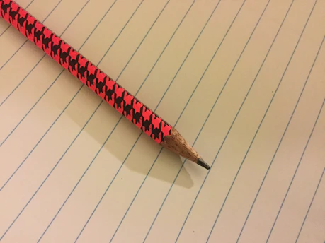 A close-up of a sharpened pencil resting on a clean, white notebook page.