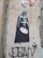 Street art on a wall depicting a character in black armor holding two heart-shaped balloons with 'Luke' and 'Leia' written on them. Next to the character, a caption reads, 'Damn... I hate holidays!' A signature or tag 'JEAN' appears at the bottom with an asterisk beside it.