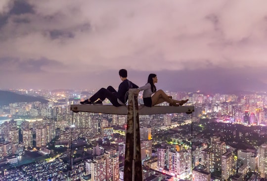 man and woman sitting on metal on top of high rise building in Shenzhen China