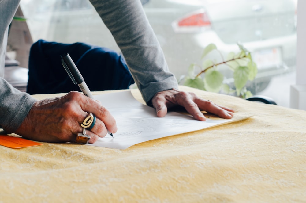 person writing on white plain paper on the table photography