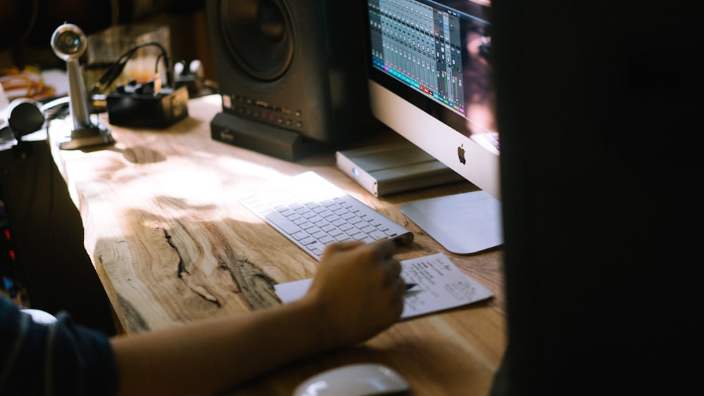 person using silver iMac, Apple Magic Keyboard, and Magic Mouse set