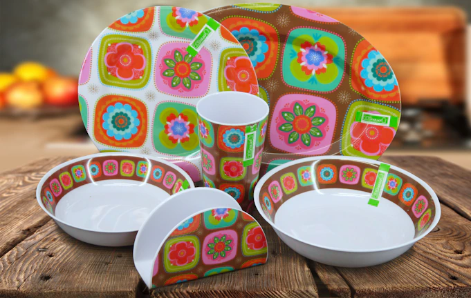 A bright table setting featuring a mix of glazed plates and cups in warm hues.